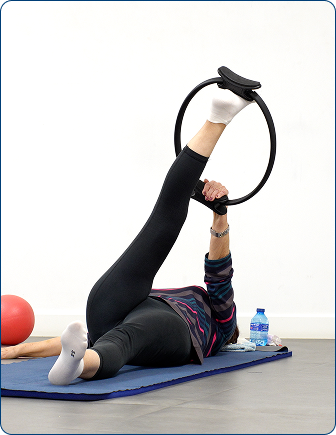 Alumna tumbada trabajando el core con un aro de pilates