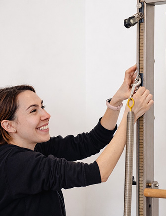 Instructora ajustando los muelles de la máquina Reformer