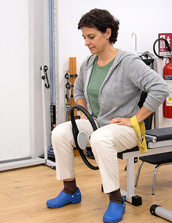 Alumna sentada trabajando con un aro de pilates y una banda elástica