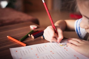 Niño escribiendo en una ficha con un lápiz rojo