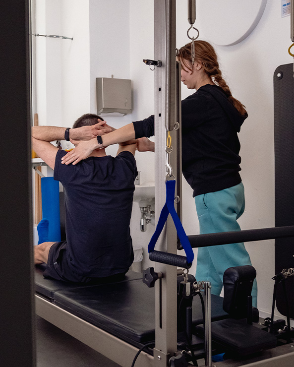 Instructora de ASERHCO guiando a un alumno en una máquina de Pilates