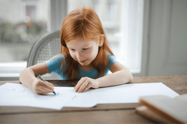 Niña escribiendo en un cuaderno sobre una mesa