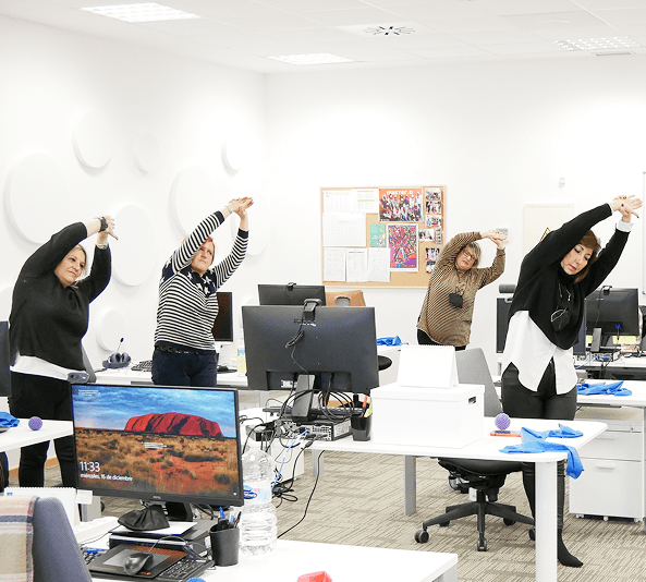 Trabajadoras realizando estiramientos junto a sus puestos de oficina